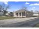 Inviting one-story house with a covered porch and light-colored exterior in a residential area with a gravel driveway at 3022 Alice Ave, Indianapolis, IN 46237