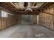 Unfinished garage with exposed insulation and rafters, concrete floor, and a gray garage door at 3022 Alice Ave, Indianapolis, IN 46237