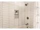 Close-up of a tiled shower/tub with decorative shelf and a stylish shower head at 3732 N Kenwood Ave, Indianapolis, IN 46208