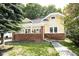 Charming yellow two-story home featuring a brick foundation, covered front porch, and well-maintained lawn at 415 Ruskin Pl, Indianapolis, IN 46205
