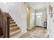 Hallway with carpeted stairs and wood floors leading to a white door and console table at 5944 Aldridge Dr, Whitestown, IN 46075