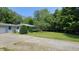 Landscaped front lawn with mature trees and decorative bushes complements the home's exterior at 6040 W Thompson Rd, Indianapolis, IN 46221