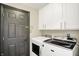 Well-organized laundry room with modern washer and dryer, white cabinets, and a dark door for convenient utility at 6571 Hunters S Rdg, Zionsville, IN 46077