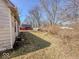 View of the backyard with a white house, mature trees, and sparse ground cover at 6616 W Thompson Rd, Indianapolis, IN 46241