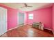 Bright pink bedroom with ceiling fan, wood floors, and large closet for storage at 6616 W Thompson Rd, Indianapolis, IN 46241