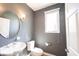 Stylish powder room featuring a pedestal sink, round mirror, and a window with natural light at 9921 N Wind River Run, McCordsville, IN 46055