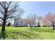 Beautiful two-story home with a stone facade, lush green lawn, and mature trees under a clear blue sky at 9921 N Wind River Run, McCordsville, IN 46055
