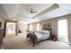 Spacious primary bedroom featuring a tray ceiling, ceiling fan, and sitting area at 9921 N Wind River Run, McCordsville, IN 46055