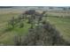 An aerial shot displays trees, greenery, and a small pond area at 10624 N 200 W, Alexandria, IN 46001