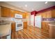 Well-equipped kitchen featuring wood cabinets, white appliances, laminate countertops, and durable wood-look flooring at 123 Bridgemor Ln, Mooresville, IN 46158