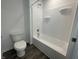 Full bathroom with white toilet, shower over tub, and gray plank flooring at 1265 Fleming Dr, Greenfield, IN 46140