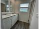 Bathroom with double sink vanity, mirror, gray plank flooring, and a window for natural light at 1265 Fleming Dr, Greenfield, IN 46140