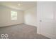 A bedroom with neutral carpet, a window, and a white door at 1618 Trichel Dr, Greenwood, IN 46143