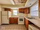 A kitchen has wood cabinets, a white refrigerator and stove, and vinyl tile flooring at 2207 E Dudley Ave, Indianapolis, IN 46227