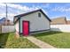 Close up of detached garage with white siding and a bright pink door, surrounded by a green yard at 2432 N Talbott St, Indianapolis, IN 46205
