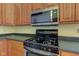 Close-up of a gas range and stainless steel microwave in a kitchen with wooden cabinets and black countertops at 2432 N Talbott St, Indianapolis, IN 46205