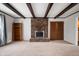 Open living room with brick fireplace, exposed beams, wood-look closet doors and neutral carpeting at 3029 Oberlin Ct, Indianapolis, IN 46268