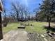 View of the backyard showing mature trees, green grass, and small house in the distance at 3120 Central Ave, Anderson, IN 46016
