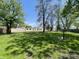 Expansive yard with lush grass, scattered trees, blue sky, and single-story house creating an inviting outdoor space at 34 W Main St, Brownsburg, IN 46112