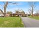 Wide view of a brick home with a long driveway, green lawn, mature trees, and a basketball hoop for outdoor recreation at 3602 N County Road 950 E, Brownsburg, IN 46112