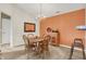 Dining area with wooden table, seating, and a decorative chandelier with an orange accent wall at 4925 Opal Ridge Ln # 309, Indianapolis, IN 46237