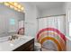 Bathroom with a modern vanity, bright lighting, and a shower with a colorful, striped curtain at 5529 W Mccord Rd, McCordsville, IN 46055