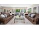 Expansive living room with leather couches, neutral carpet, and glass table, leading to an outdoor view at 9080 Pickwick Dr, Indianapolis, IN 46260