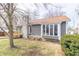 Exterior view of a one-story home with gray siding, stone chimney, and a cozy sunroom with ample natural light at 953 S 5Th St, Noblesville, IN 46060
