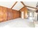 Cozy living room with wood-paneled accent wall, neutral carpet, beamed ceilings, and doorway to the kitchen at 953 S 5Th St, Noblesville, IN 46060
