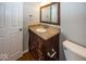 Bathroom vanity with a brown cabinet, stone countertop, a mirror, and a white door and toilet at 11849 Wapiti Way, Noblesville, IN 46060