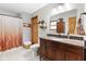 Well-lit bathroom with a granite countertop vanity, a toilet, and a tiled shower with an orange curtain at 12129 N Cedarview Dr, Mooresville, IN 46158