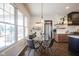Sunlit dining area features a glass table, leather chairs, and large windows overlooking the yard at 13947 Morningtide Cir, Fishers, IN 46038
