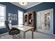 Cozy home office with a dark blue accent wall, stylish desk, and french doors at 13947 Morningtide Cir, Fishers, IN 46038