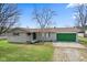 Charming single-story home features a green garage door, a well-maintained lawn, and mature trees at 1620 S East St, Lebanon, IN 46052