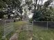 View of the backyard with a partial fence, some trees, and an overgrown lawn at 2820 N Gladstone Ave, Indianapolis, IN 46218