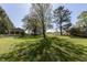 Lush green backyard with mature trees, a swing set, and a charming cottage at 3548 W 500 North Rd, McCordsville, IN 46055