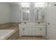 Bright bathroom featuring a double vanity with framed mirrors and a soaking tub with tile surround at 3792 Waterfront Way, Plainfield, IN 46168