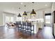 Bright kitchen with white cabinets, dark hardwood floors, and an island with seating under pendant lighting at 4052 Saddle Club S Pkwy, Bargersville, IN 46106