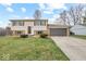 Split-level home showcasing a front yard, a two-car garage, and a combination of stone and siding at 4448 Aristocrat Cir, Indianapolis, IN 46235