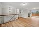 Living area displaying hardwood floors, staircase, and entry to kitchen and outdoor balcony at 4448 Aristocrat Cir, Indianapolis, IN 46235