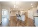 Open-concept view of the white kitchen, living, and dining rooms with hardwood floors and barstool seating at 4720 W Tradwell Dr, New Palestine, IN 46163