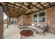 Inviting covered patio with exposed wood beams, fan, brick surround, stylish seating, and comfortable furnishings at 4720 W Tradwell Dr, New Palestine, IN 46163