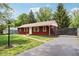 A charming red home featuring mature trees, a well maintained lawn, and a paved driveway at 4754 E 64Th St, Indianapolis, IN 46220