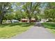 View of a home across a grassy lawn with mature trees and a long driveway at 4754 E 64Th St, Indianapolis, IN 46220