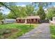 A charming red home featuring mature trees, a well maintained lawn, and a paved driveway at 4754 E 64Th St, Indianapolis, IN 46220
