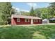 The red home features a well kept yard, white trim around the windows, and mature trees at 4754 E 64Th St, Indianapolis, IN 46220