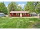 Charming red home featuring a well-manicured lawn, and mature trees at 4754 E 64Th St, Indianapolis, IN 46220
