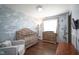 Bedroom featuring stylish wave wallpaper, hardwood floors, wooden crib, and changing table at 5415 Wallace Ave, Indianapolis, IN 46220