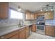 Kitchen with stainless steel appliances, wooden cabinets, mosaic tile backsplash, and tile flooring at 5415 Wallace Ave, Indianapolis, IN 46220