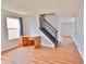 Open living space featuring laminate flooring, a staircase with dark banister, and a window with blue curtains at 5944 Edelle Dr, Indianapolis, IN 46237